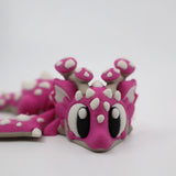Pink 3D printed flexi dragon fidget toy with white spikes and big eyes for sensory play
