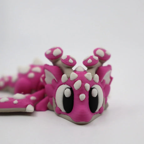 Pink 3D printed flexi dragon fidget toy with white spikes and big eyes for sensory play