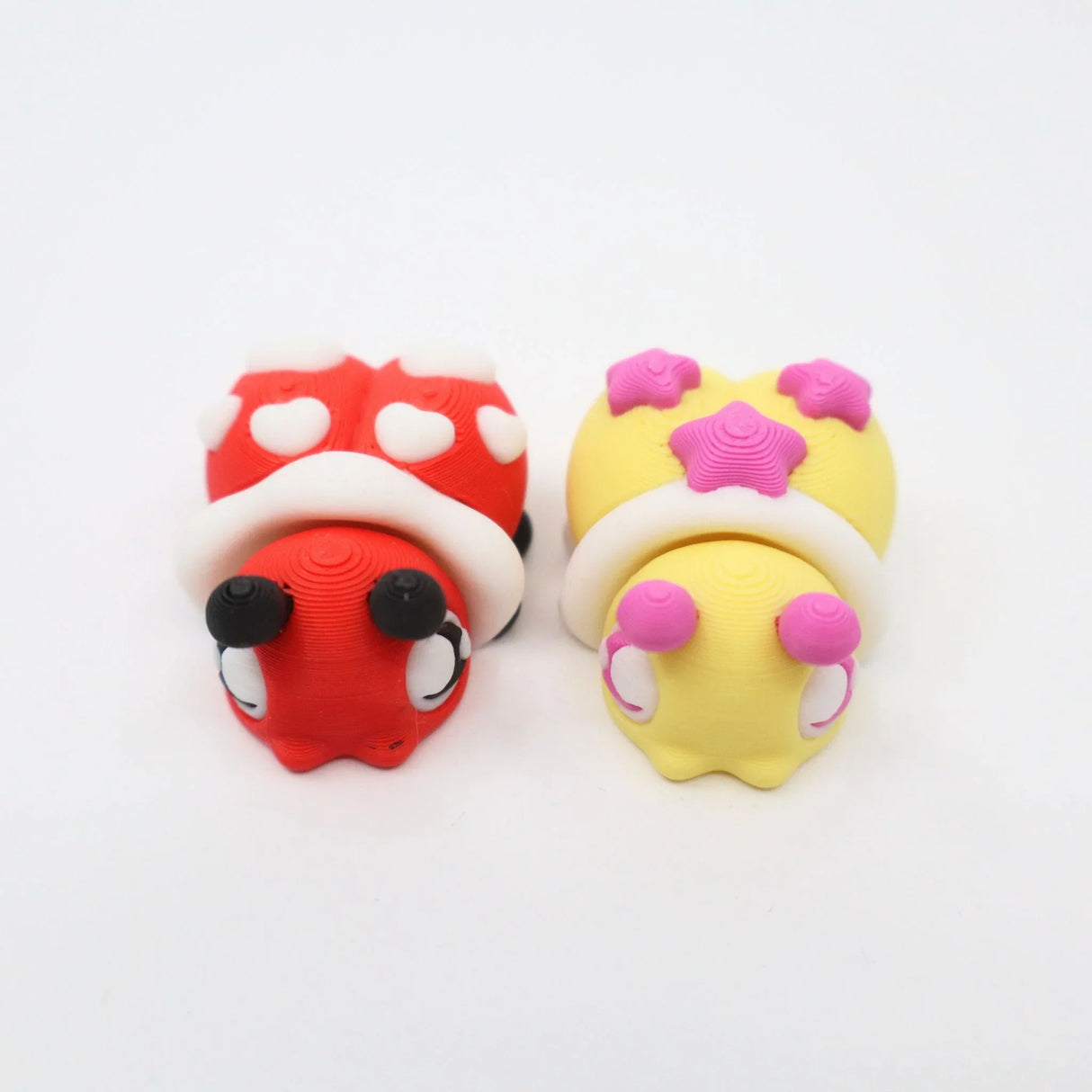 Two colorful 3D printed mushroom house sensory toys with heart and star patterns