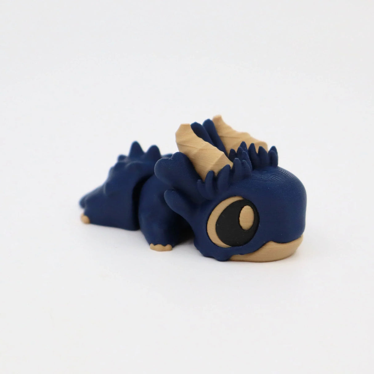 Blue and beige 3D printed sensory dragon toy with large eyes on white background