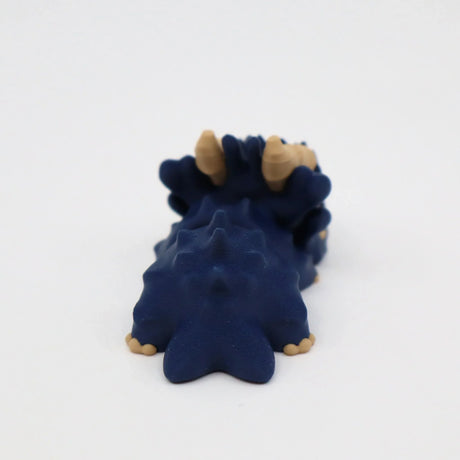 Blue 3D printed sensory dinosaur toy with beige horns on a white background