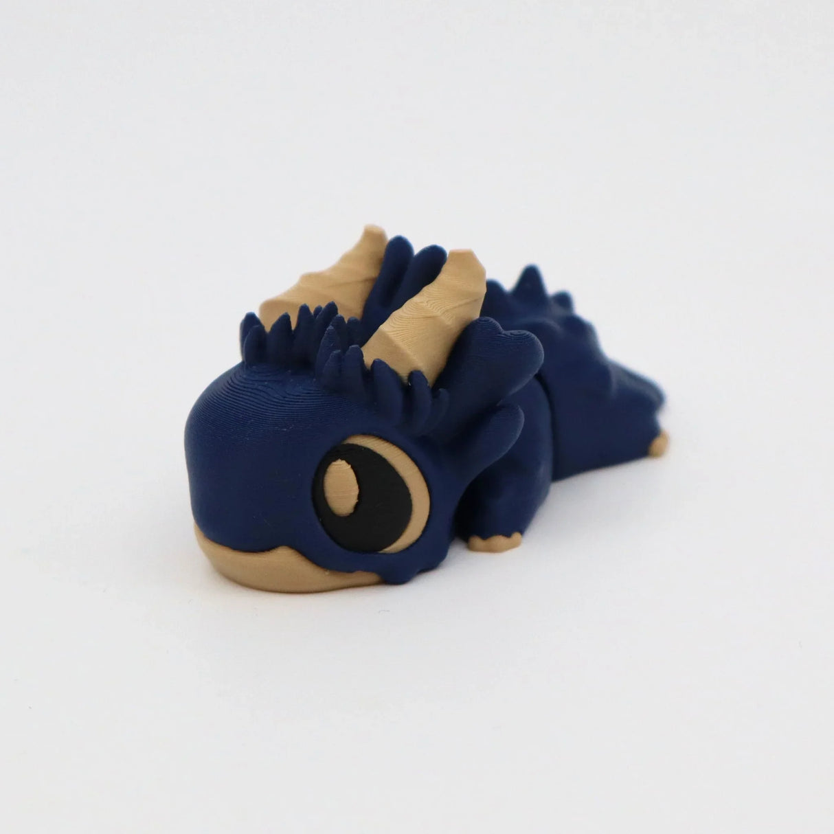 Blue and tan 3D printed dragon sensory toy with big eyes on white background