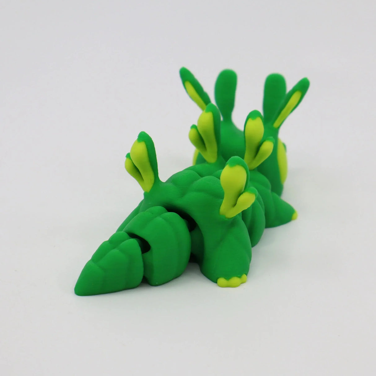 Green and yellow 3D printed sensory toy shaped like a segmented sea slug on white background