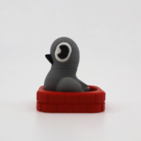 Gray penguin sensory fidget toy in red brick base, 3D printed for tactile play
