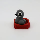 Gray 3D printed penguin fidget toy in red brick base, sensory-friendly design for kids