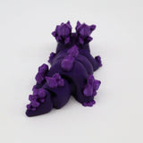 Purple 3D printed sensory toy shaped like a crystal-covered dinosaur on white background.