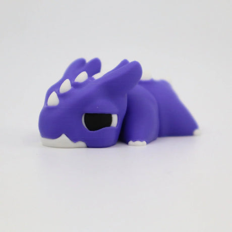 Purple 3D printed sensory dragon toy with white horns and black eyes on white background.