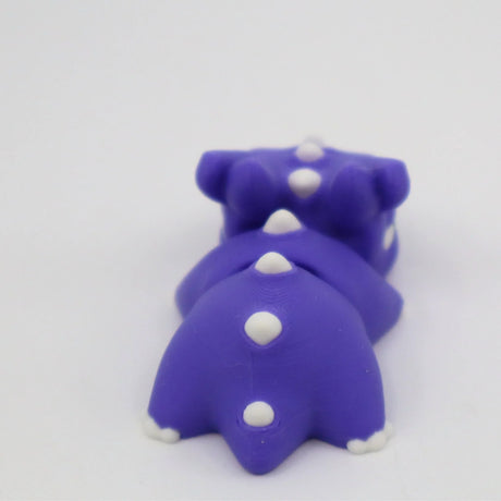 Purple 3D printed dinosaur sensory toy with white spikes on a white background