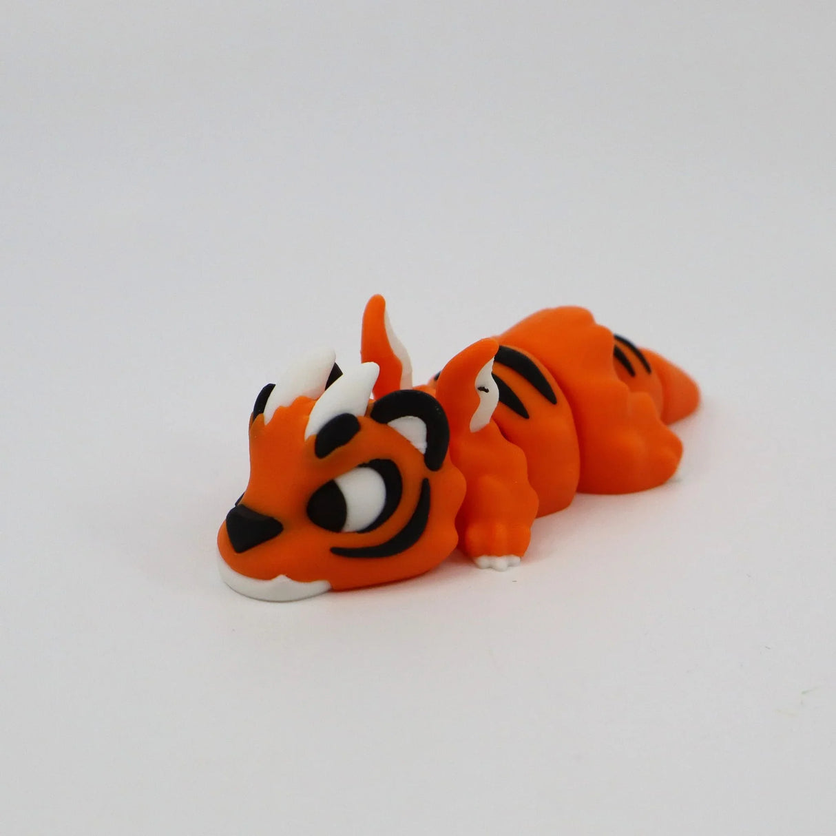 Orange 3D printed tiger sensory fidget toy with black stripes, lying on white background