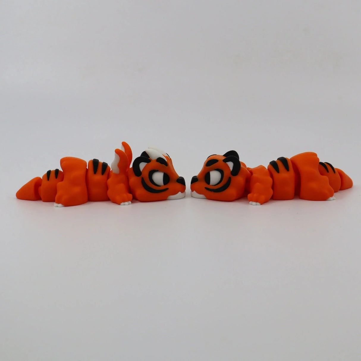 Two orange 3D printed tiger fidget toys facing each other on a white background