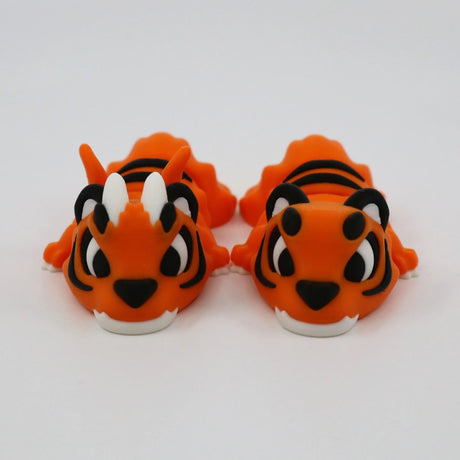 Pair of orange 3D printed sensory tiger toys with black stripes on a white background