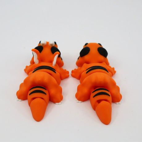 Two orange 3D printed sensory tiger toys with black stripes, viewed from behind