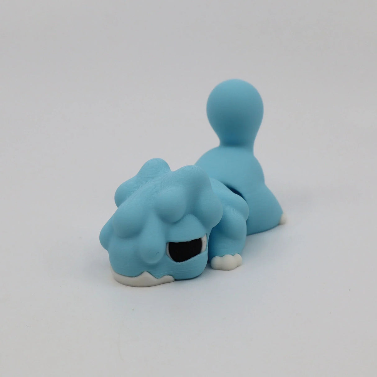 Blue 3D printed sensory toy lizard with textured back and curled tail on white background