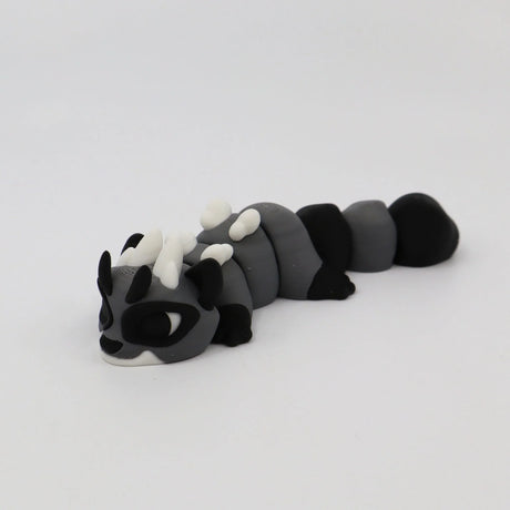 Gray and black 3D printed sensory toy caterpillar with white horns on white background