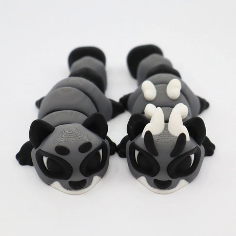 Two gray and black 3D printed sensory animal fidget toys with white horns on a white background