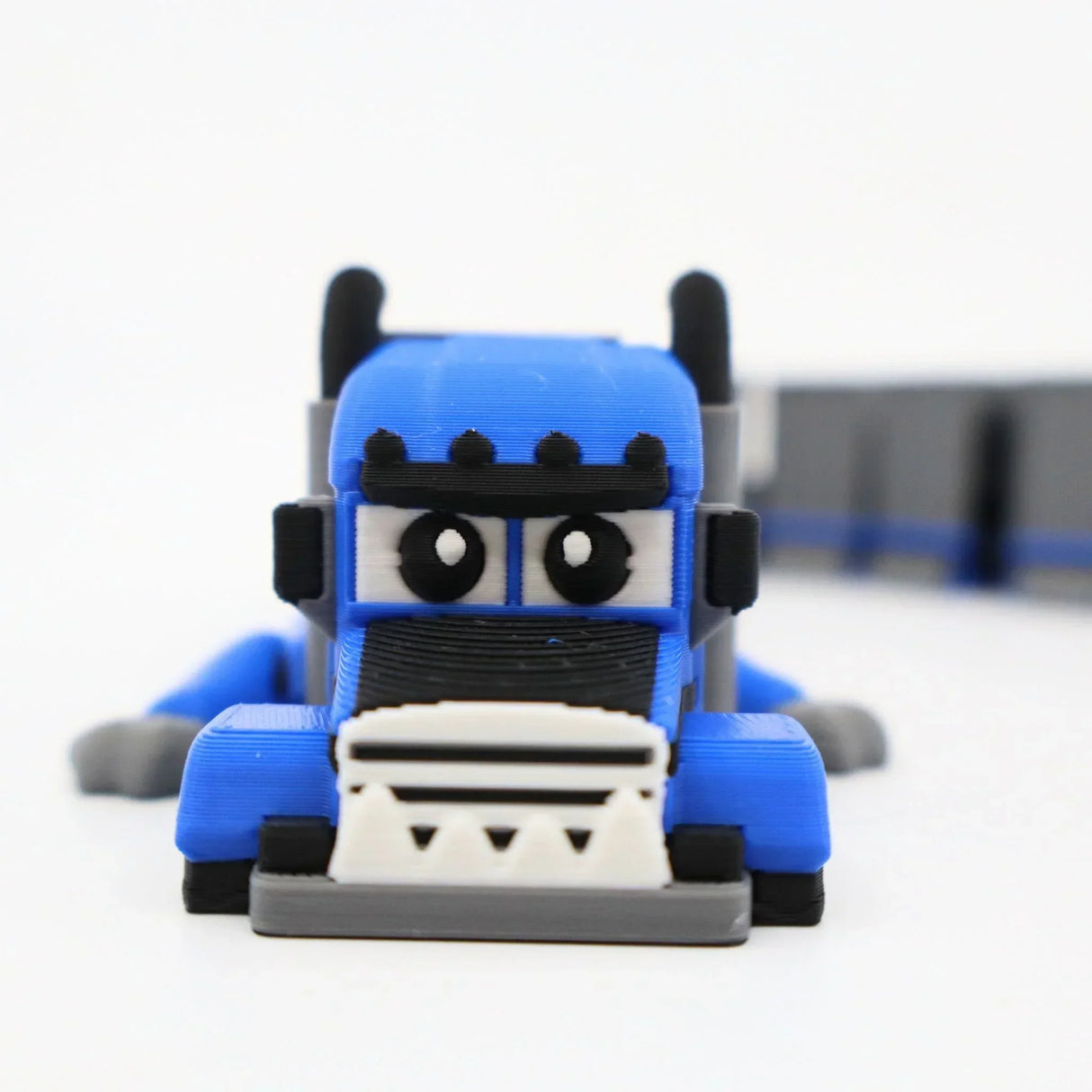 Blue 3D printed semi truck fidget toy for sensory play, featuring cartoon eyes and clickable details