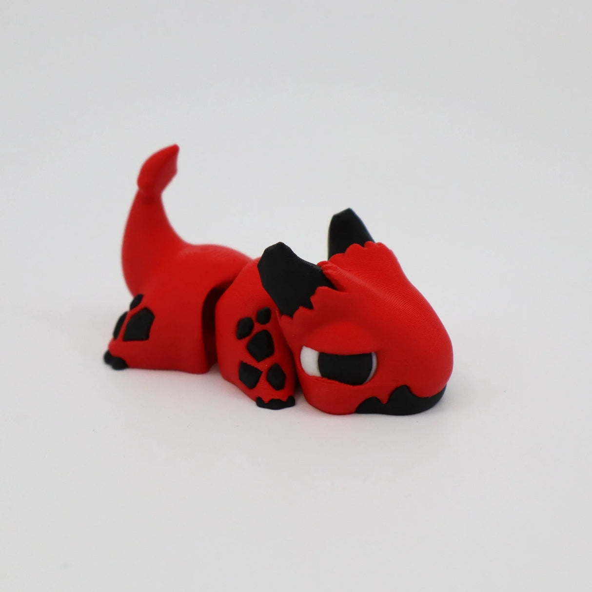Red and black 3D printed dragon sensory toy with flexible joints on white background