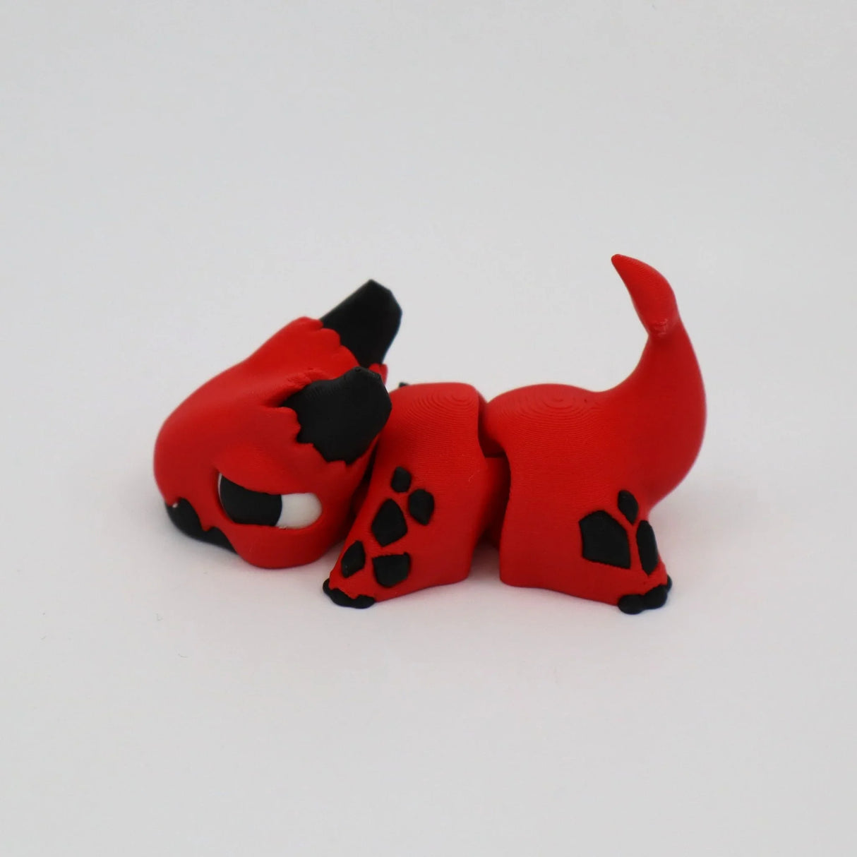 Red and black 3D printed sensory toy cat with segmented body on white background