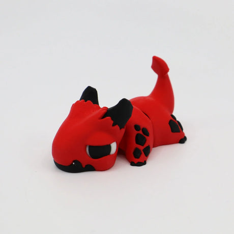 Red and black 3D printed dragon sensory toy lying on white background