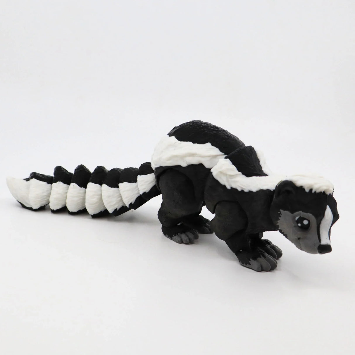 3D printed black and white skunk sensory toy with articulated tail on white background