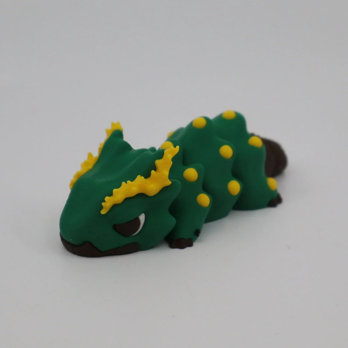 Green and yellow 3D printed sensory lizard toy with textured spikes on white background