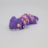 Purple gecko-shaped sensory toy with pink sprinkle-like details, 3D printed, on white background