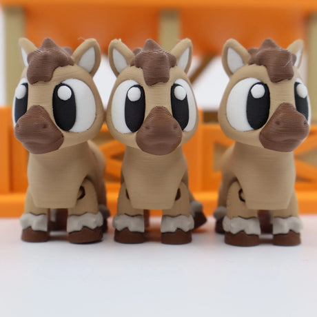Three cute 3D printed horse sensory toys with big eyes in front of an orange fence.