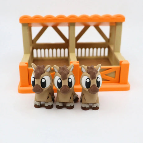 Three cute 3D printed horse toys in front of an orange sensory toy stable