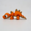 Orange 3D printed stegosaurus sensory toy with flexible joints on white background