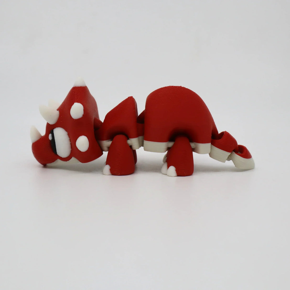 Red and white 3D printed triceratops sensory toy with articulated limbs on white background