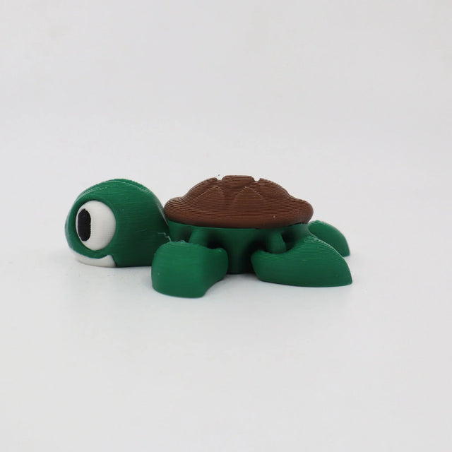 Green and brown 3D printed turtle sensory toy with large eyes on white background.