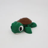 3D printed green and brown turtle sensory toy on a plain white background