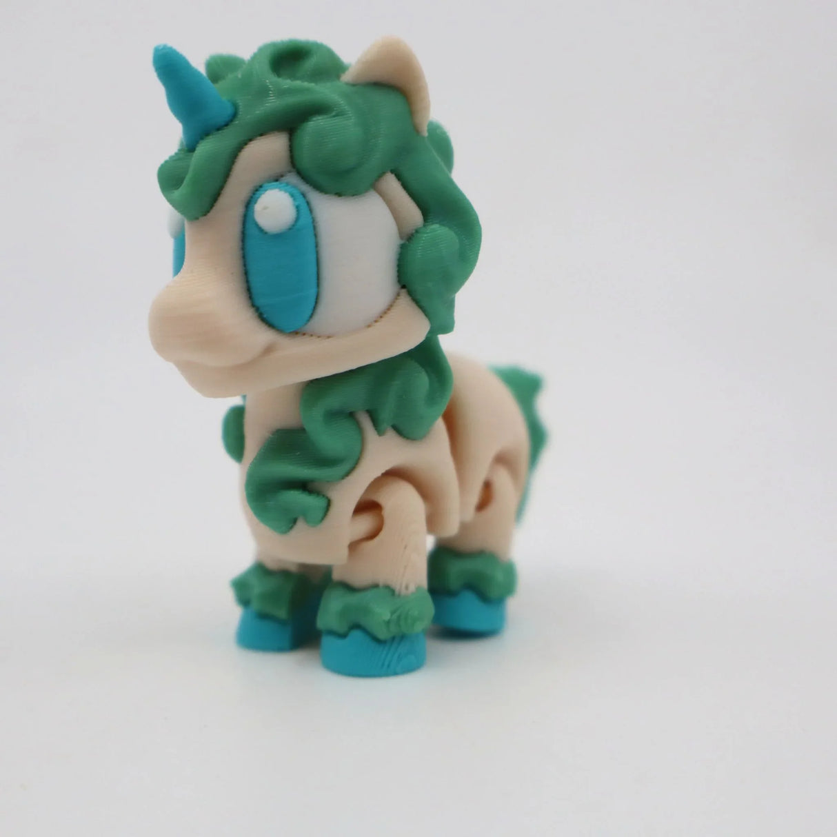 Colorful 3D printed unicorn sensory toy with green mane and blue eyes on white background