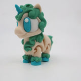 Colorful 3D printed unicorn sensory toy with green mane and blue eyes on white background