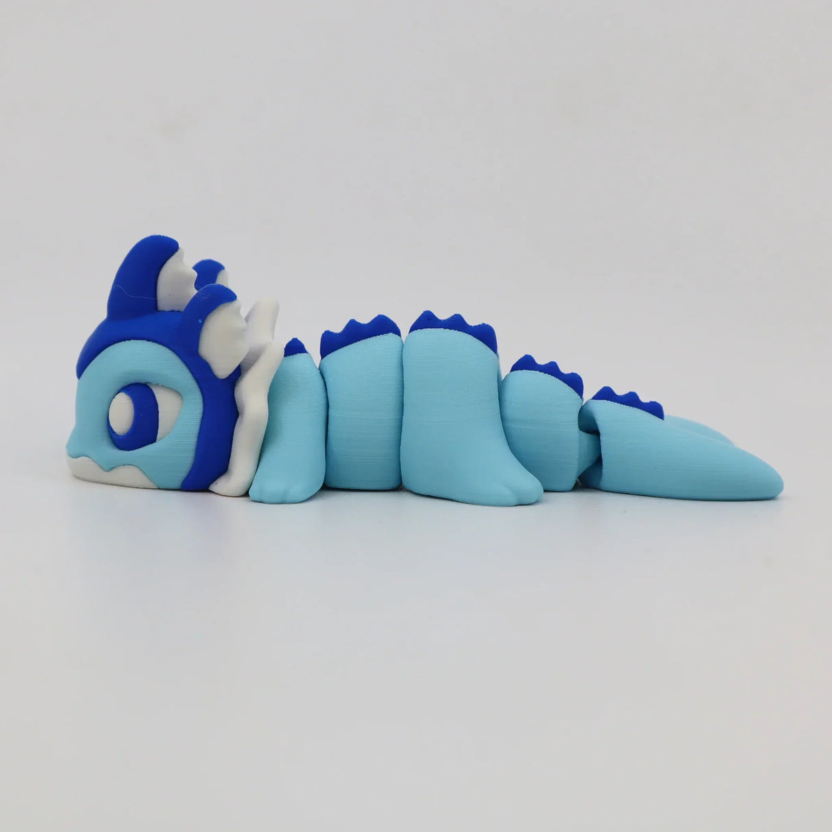Blue and white 3D printed sensory dragon fidget toy with segmented body on white background