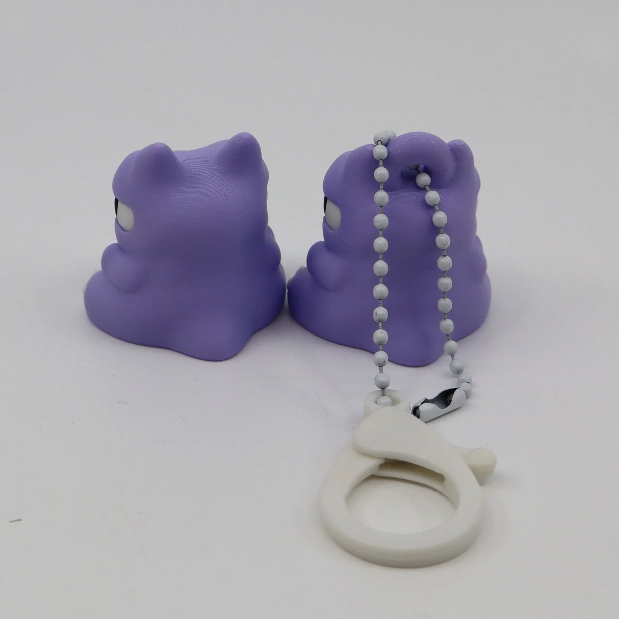 Pair of purple 3D printed animal fidget toys with a white sensory keychain on white background