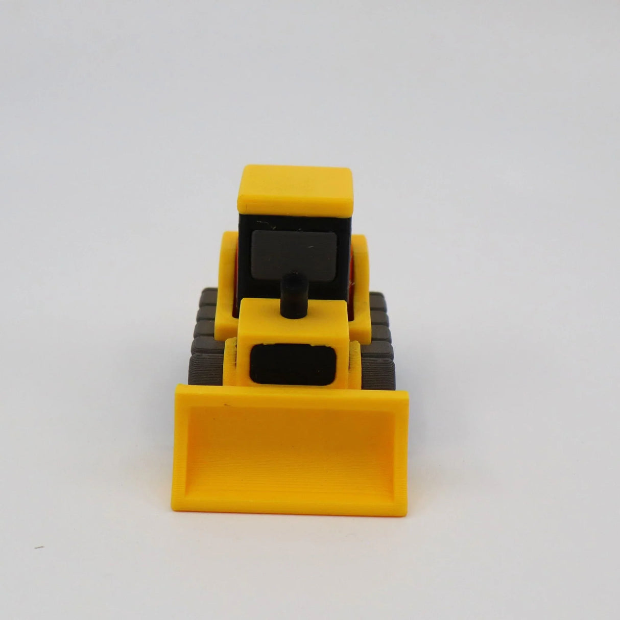3D printed yellow toy bulldozer on white background, sensory educational tool for kids
