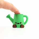 Adorable green 3D printed watering can fidget toy with cute face, perfect for sensory play and stress relief.