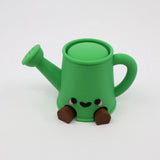 Green 3D printed watering can fidget toy with cute face and brown feet, sensory-friendly design